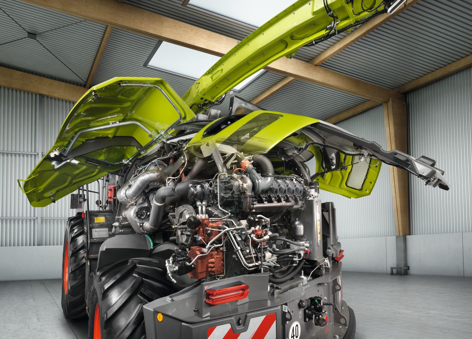 A detailed view of the internal components of a Jaguar forage harvester. The rear section is open, exposing the engine, exhaust system, and hydraulic parts.
