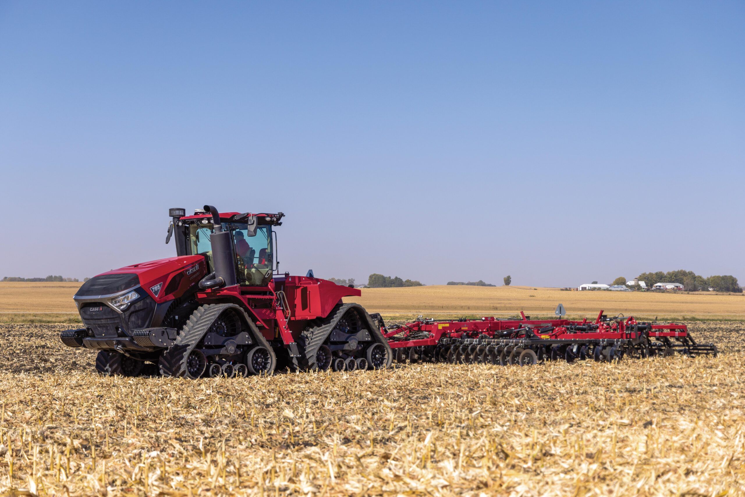  The new Steiger 785 Quadtrac pulling a wide piece of farming equipment in a field 