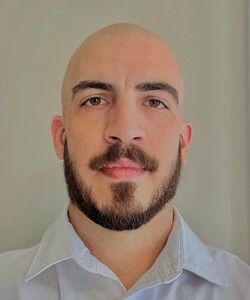 Headshot of young, bald white man with beard