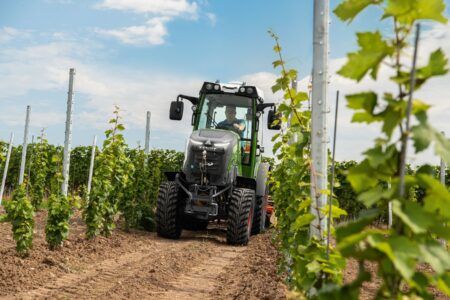 An operator in the Fendt e100 electric tractor in a vineyard