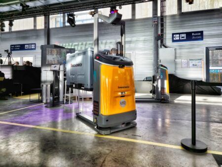 Jungheinrich launches autonomous mobile robot for high-lift applications A yellow and grey Jungheinrich EAC 212a autonomous mobile robot with a raised mast, displayed on a warehouse floor with Jungheinrich branding visible in the background