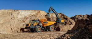 A yellow Hyundai HA45A 4x4 articulated dump truck being loaded with earth by a Hyundai crawler excavator in a quarry