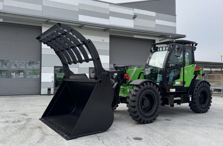 Photograph of a green Sennebogen 360 G telehandler with raised boom, parked outside an industrial building.