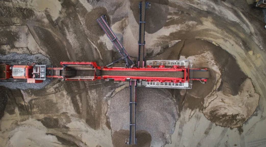 Overhead drone view of a red Finlay 694 inclined screen separating aggregate into stockpiles on a quarry floor