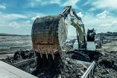 CASE STUDY: Liebherr’s smallest mining excavator White Liebherr R 9100 mining excavator in backhoe configuration tipping a large bucket of material into a loading area at an open-cast mine