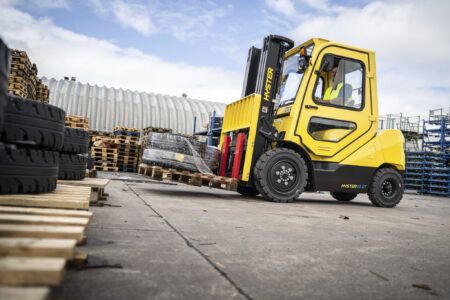 Hyster launches XTLG lithium-ion forklift series in the Americas Yellow Hyster 65 XT forklift being operated outdoors among stacked pallets and tyres at an industrial site.