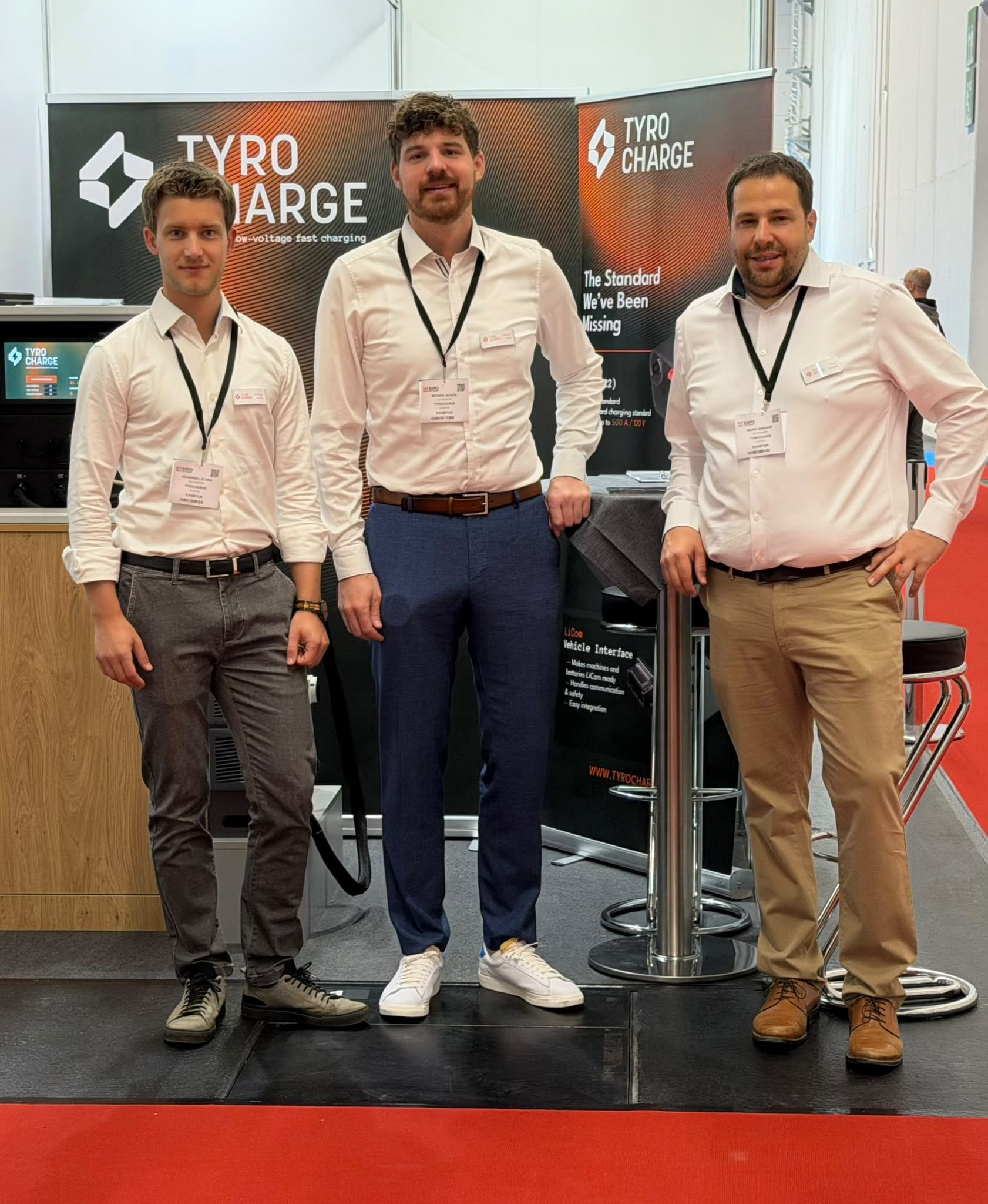 Three members of the TyroCharge team standing at the company's exhibition stand at iVT Expo Cologne
