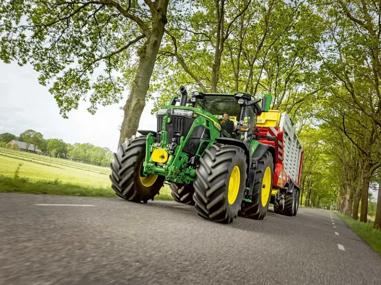 John Deere updates 6R Large and Xtra Large Frame tractor range John Deere 6R large frame tractor towing a red and yellow trailed implement along a tree-lined road