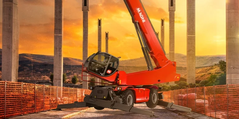 Red Magni RTH 8.46 TC rotating telehandler with boom raised and stabilisers down, on a construction site among concrete piers at sunset