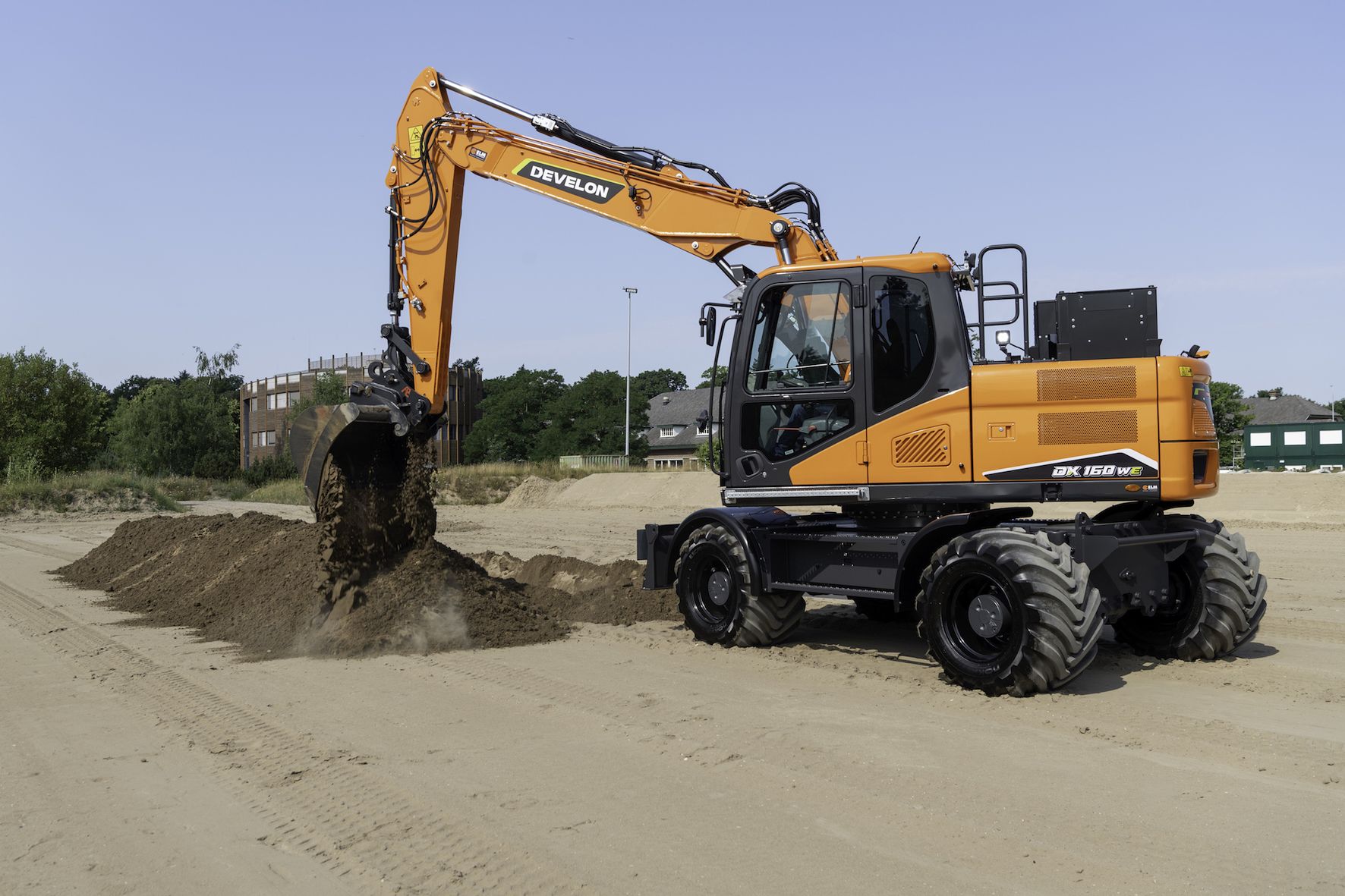 Orange Develon DX160WE electric wheeled excavator moving soil on a level worksite