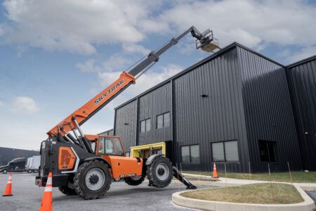 JLG redesigns SkyTrak telehandlers Orange and black JLG SkyTrak 12054 telehandler with its boom extended to a rooftop outside a dark industrial building