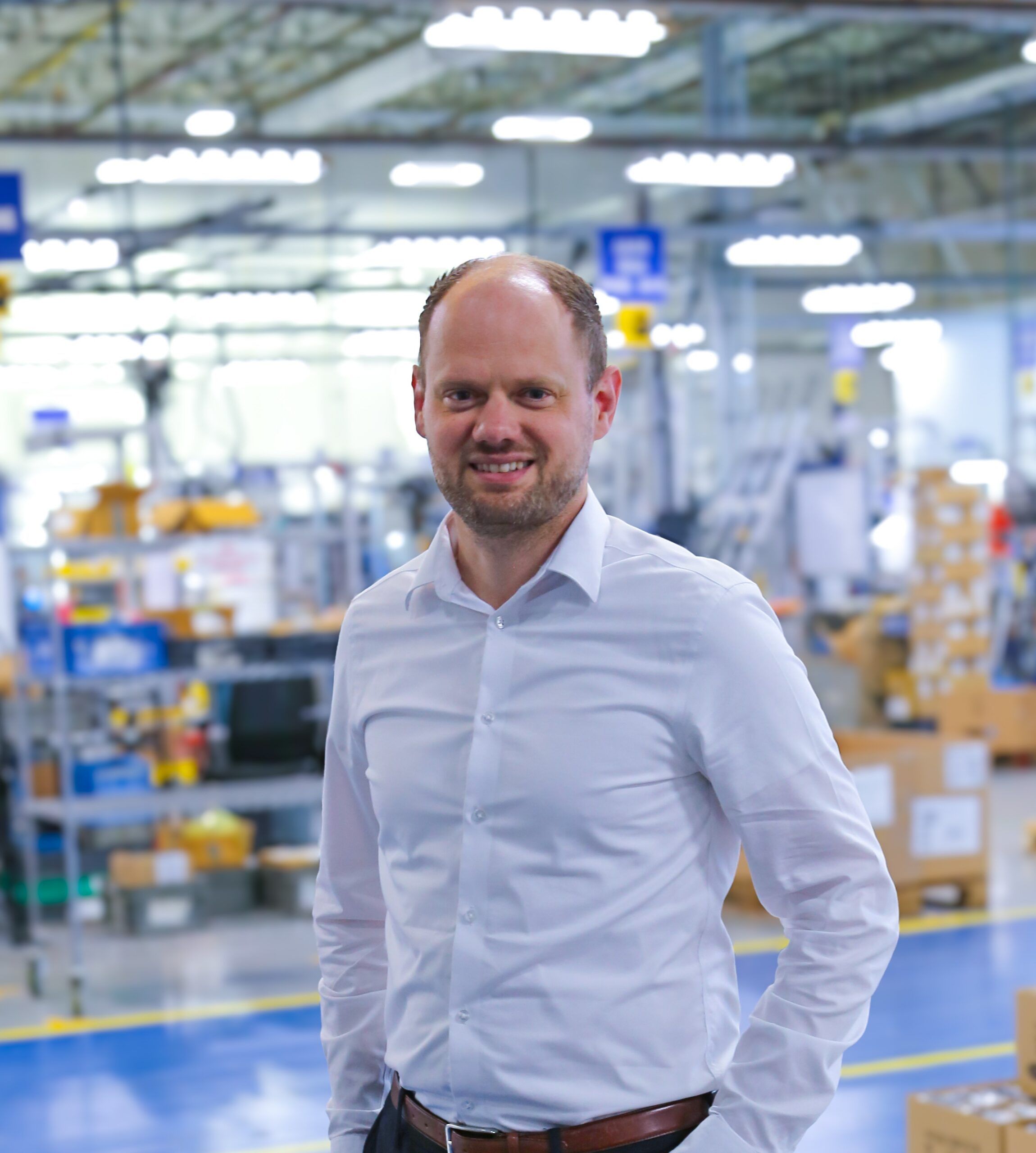 Magnus Conradsen, in a white shirt, standing in a Linak assembly and production hall