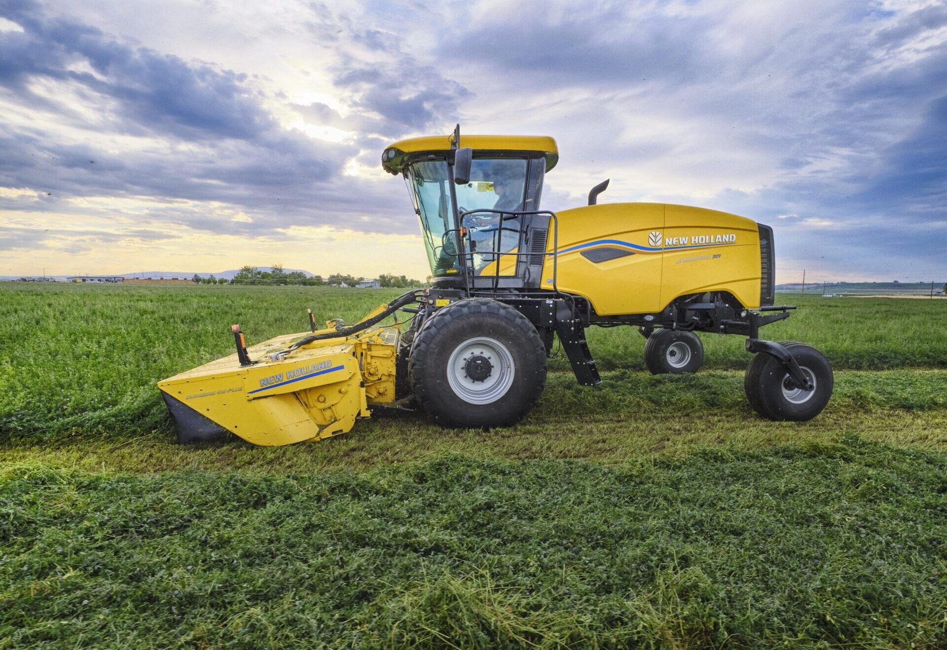 New Holland Speedrower windrower mowing a forage crop under a cloudy sky