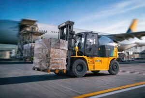 Yellow Hyundai 130B-X electric forklift carrying a shrink-wrapped pallet on an airport apron