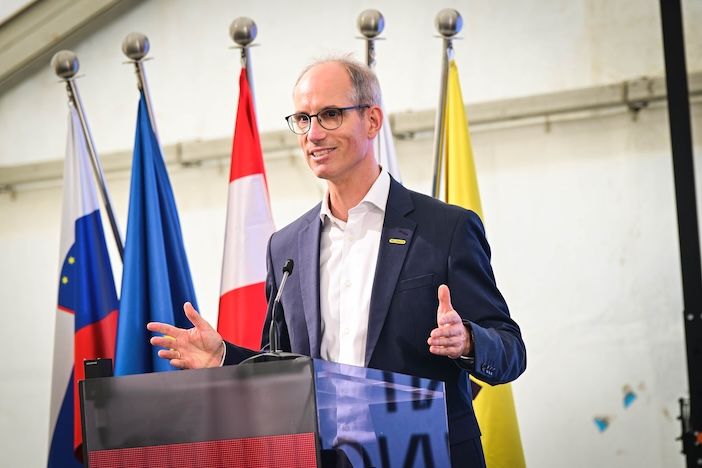 Alexander Susanek, chief operating officer of Palfinger, speaks at a lectern in front of Slovenian, EU, Austrian and Palfinger flags at the Ormož groundbreaking ceremony