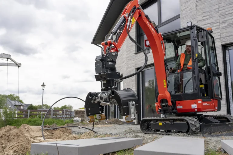Orange Kubota KX019-5 compact excavator working on a residential site, lifting a concrete slab