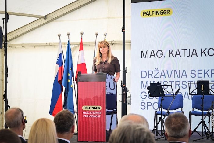 Katja Koren, state secretary at Slovenia's Ministry of the Economy, Labour and Sport, speaks at a red Palfinger-branded lectern with a screen showing her name and title behind her