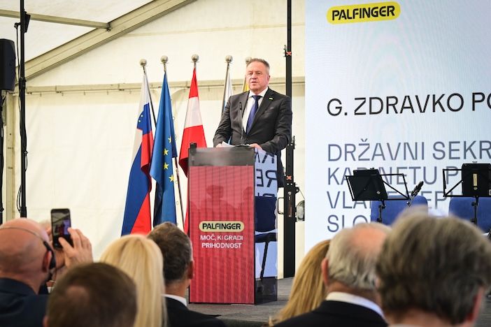 Zdravko Počivalšek, state secretary in the cabinet of the prime minister of Slovenia, speaks at a red Palfinger-branded lectern with a screen showing his name and title behind him