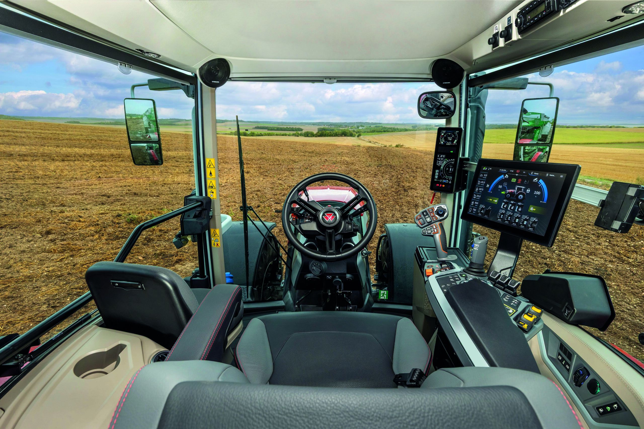 Interior of the Massey Ferguson 7S Mark 2 cab showing the steering wheel, armrest controls and Datatronic 6 touchscreen.
