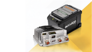 An Acculon 12V 80Ah sodium-ion battery in a black casing with an orange logo, pictured beside a finned aluminium Delta-Q charger with status indicators and power connectors, on a yellow and white background.