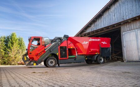 Trioliet to expand self-propelled feed mixer range at EuroTier A red Trioliet Triotrac self-propelled feed mixer working beside a timber barn, with cattle feeding at the barn entrance.